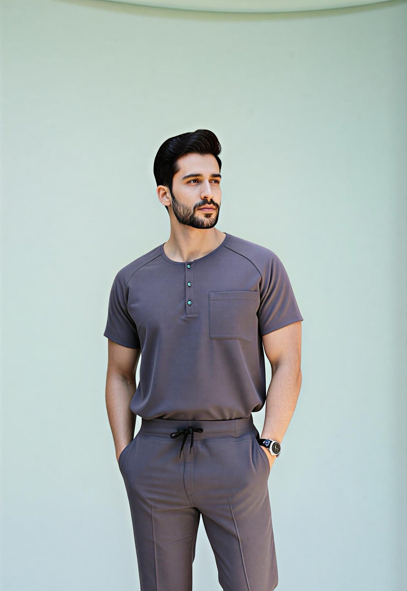 Man wearing a gray outfit standing against a light green background