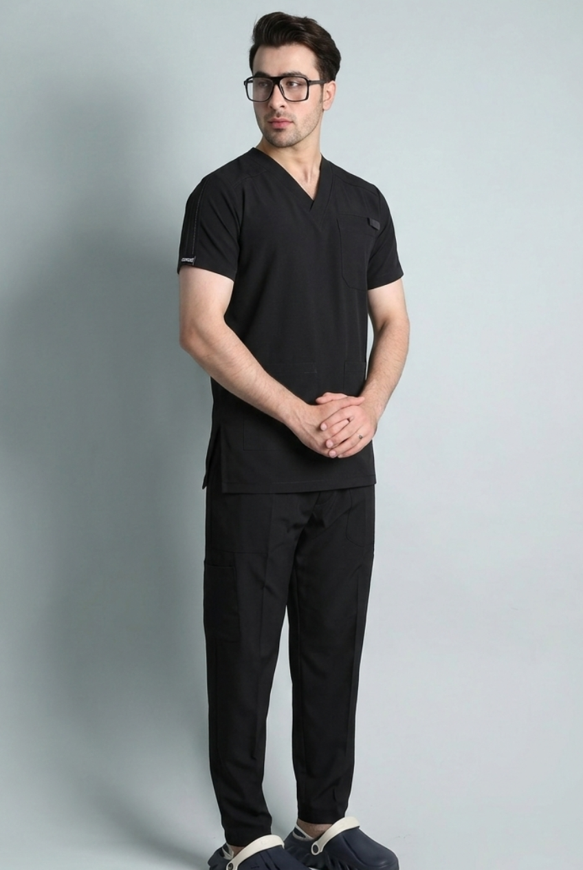 Man wearing a black scrub set against a gray background