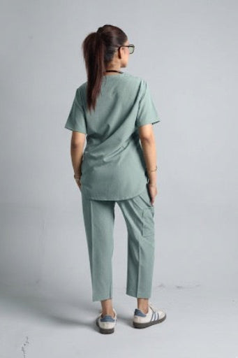 Person wearing a green scrub set on a plain background