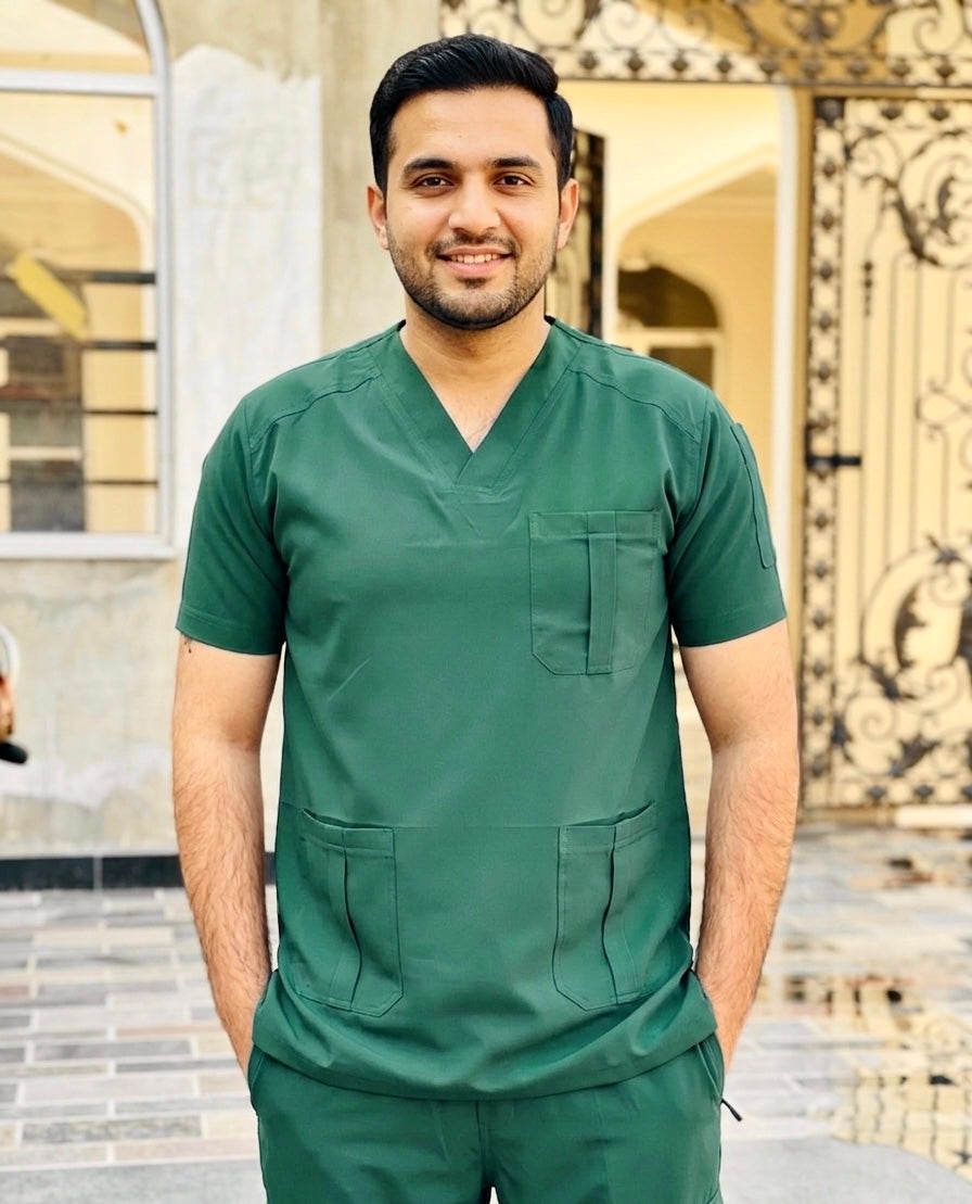 Man wearing a green scrub set standing outdoors.