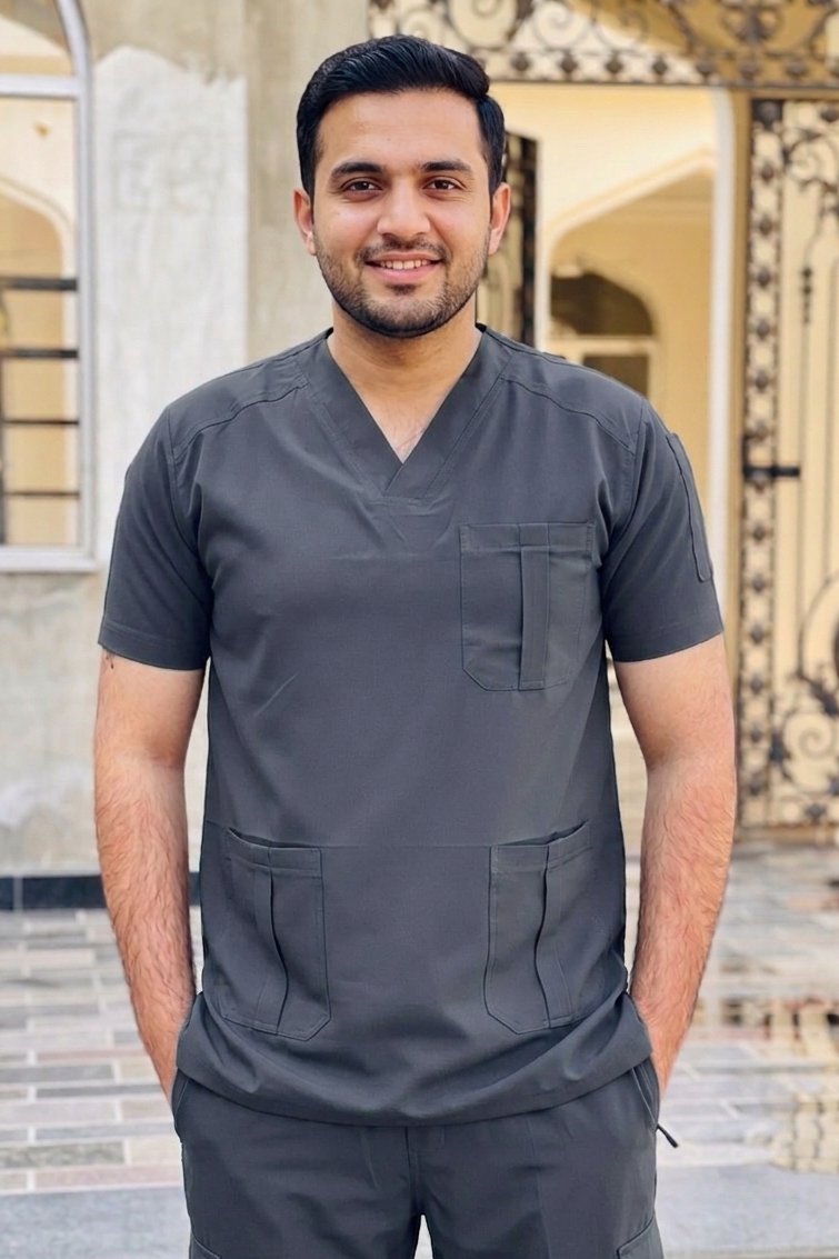 Man wearing a dark gray scrub set standing in front of an architectural background