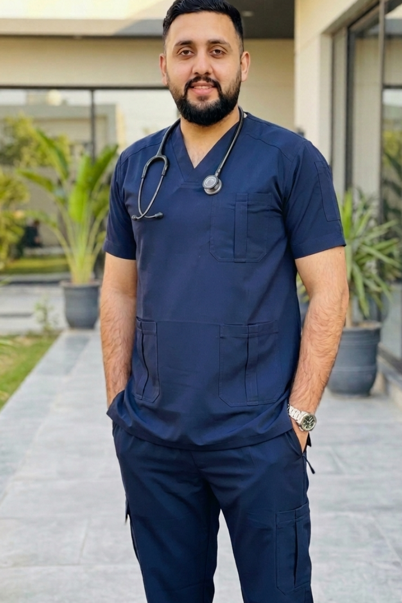 Man in navy blue medical scrubs with a stethoscope standing outdoors.