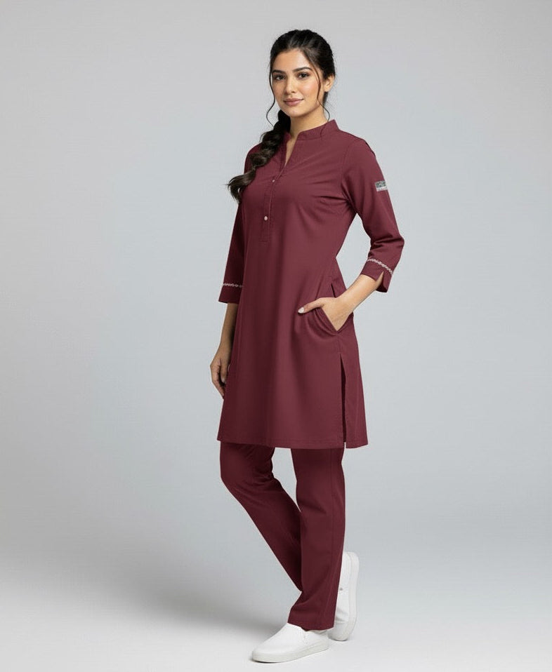 Woman wearing a maroon medical scrub set on a gray background