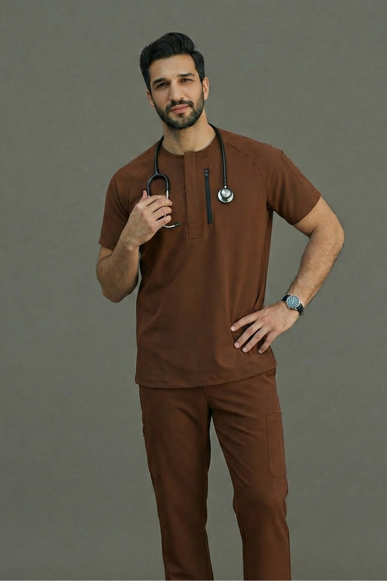 Man wearing brown medical scrubs with a stethoscope on a gray background