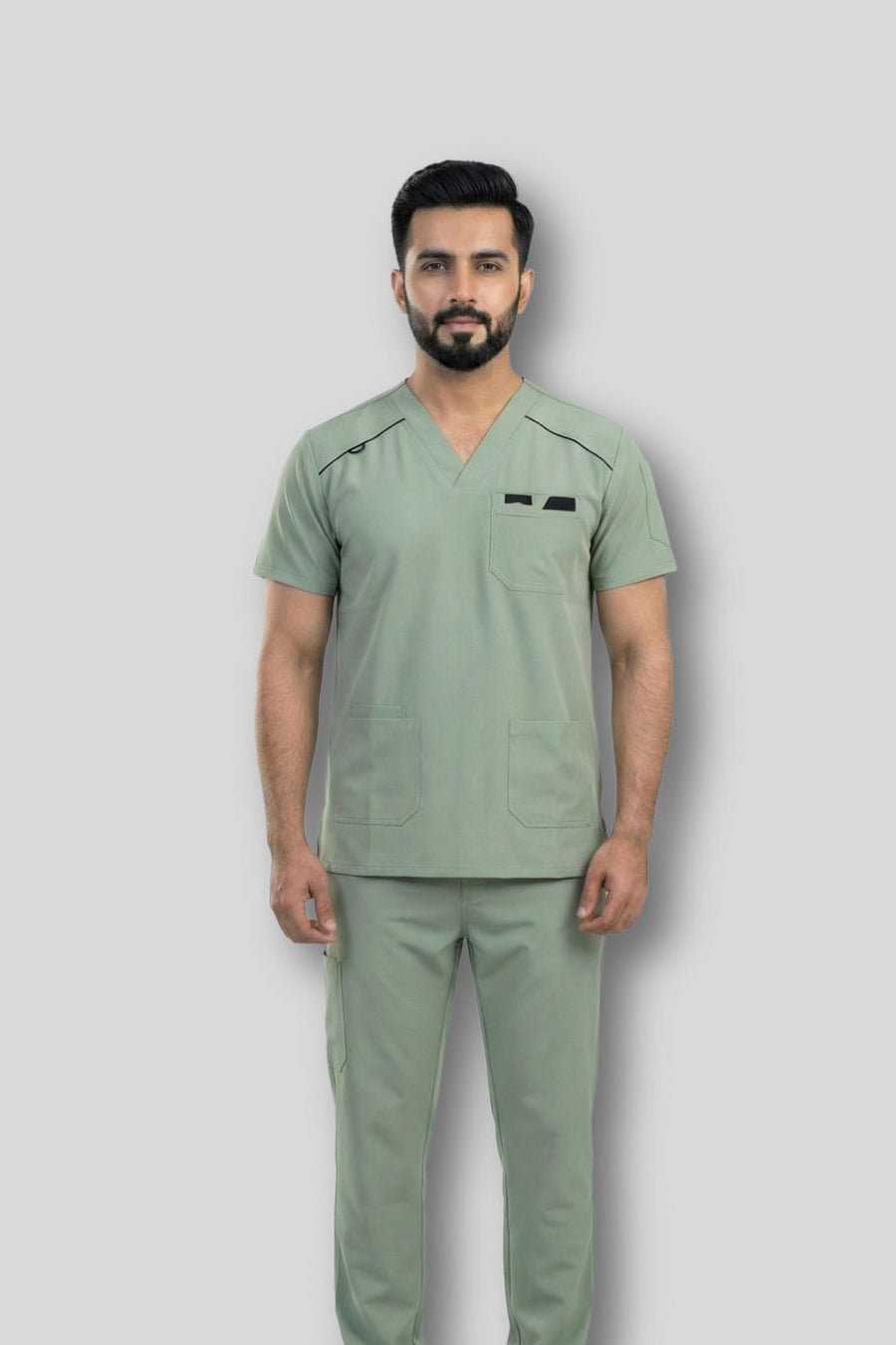 Man wearing a green scrub set against a gray background