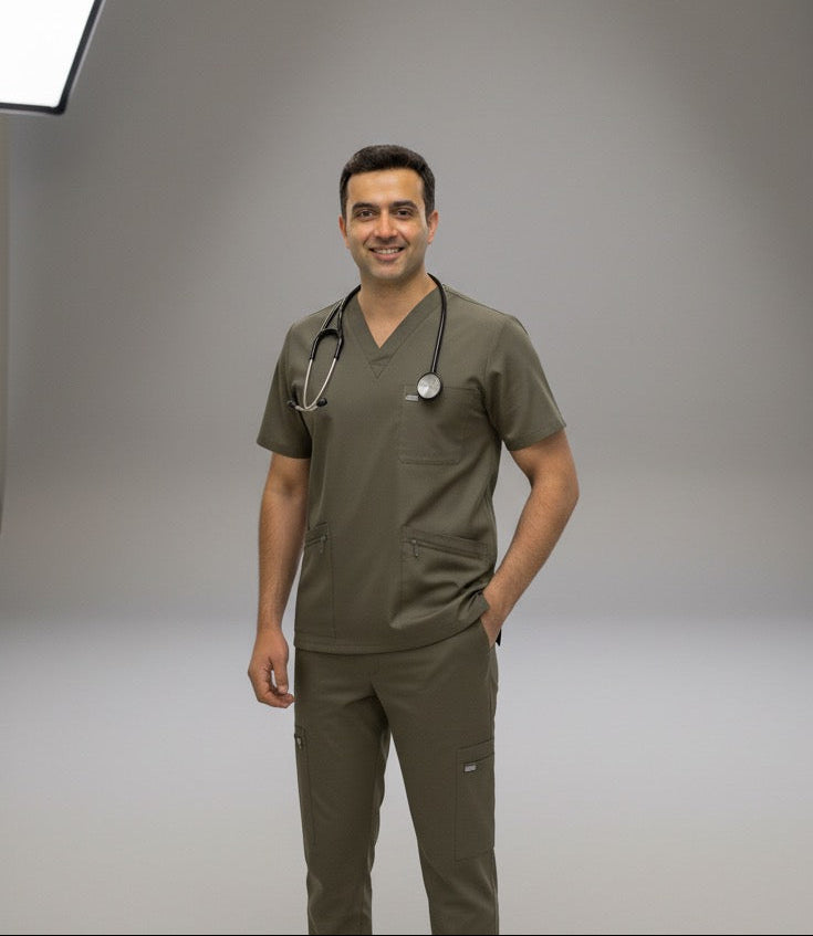 Man in medical scrubs standing in a studio with lighting equipment.