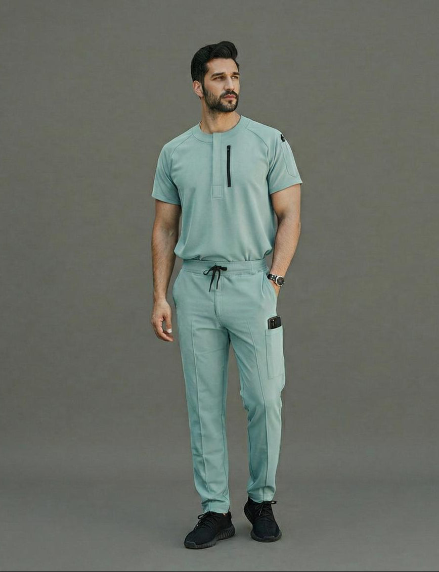 Man wearing a teal outfit standing against a gray background
