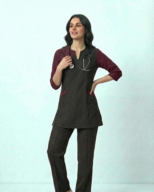 Woman wearing a dark scrub set with a stethoscope on a light gray background