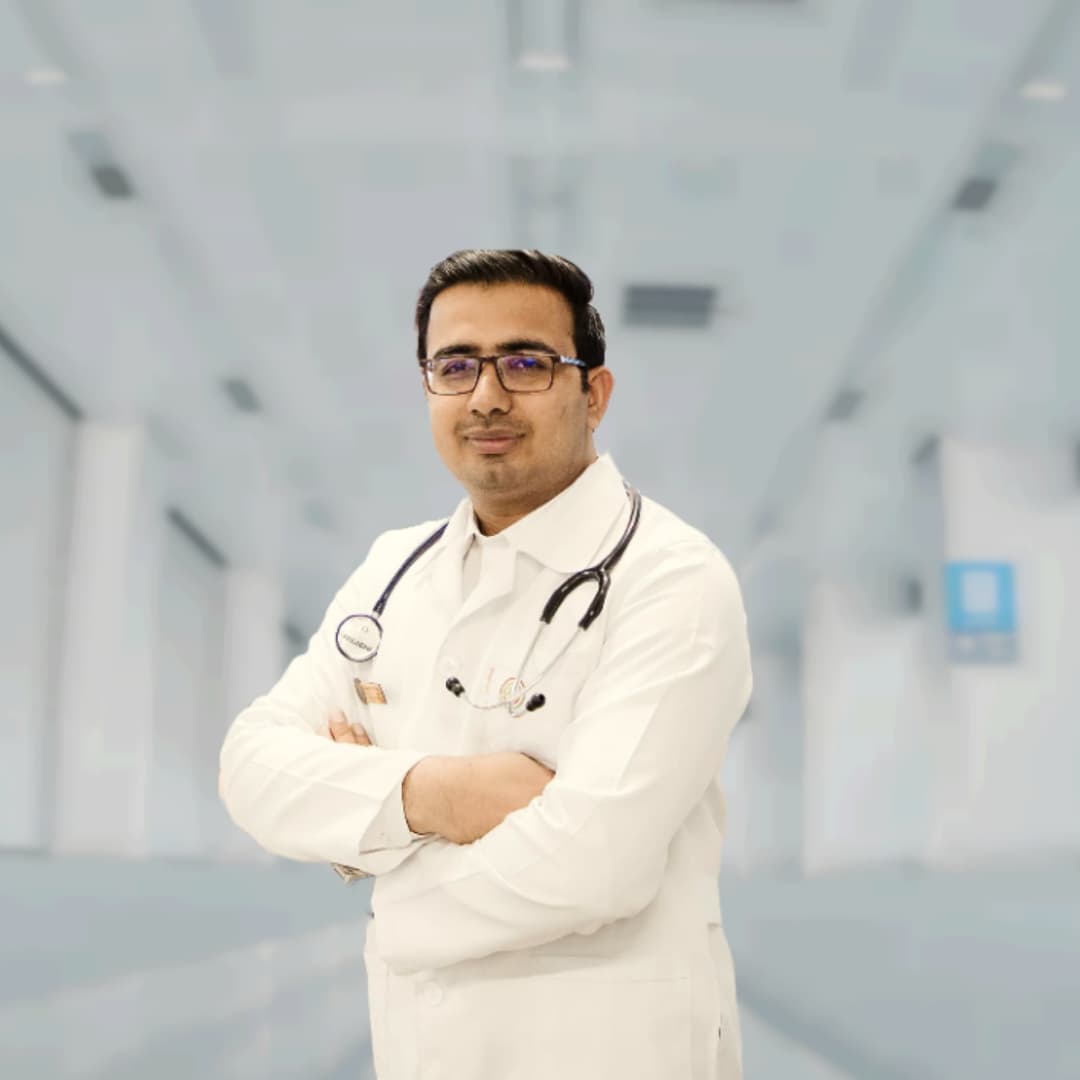 Doctor in a white coat with a stethoscope, standing in a hospital setting.