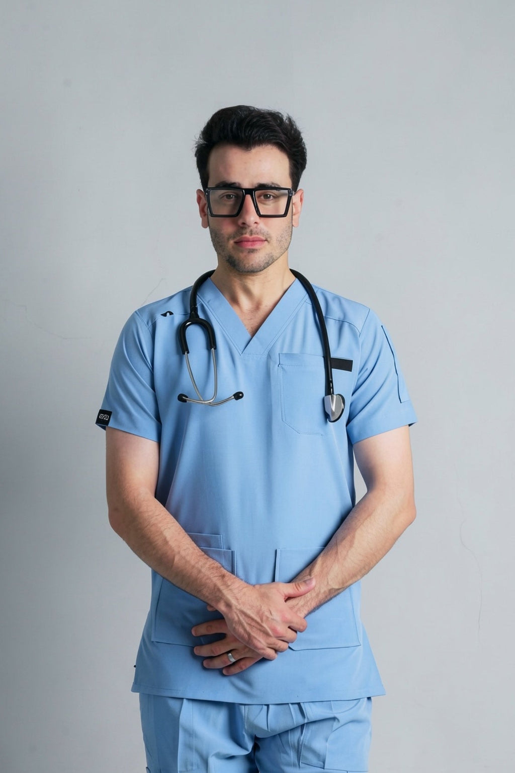 Person wearing light blue medical scrubs with a stethoscope on a gray background