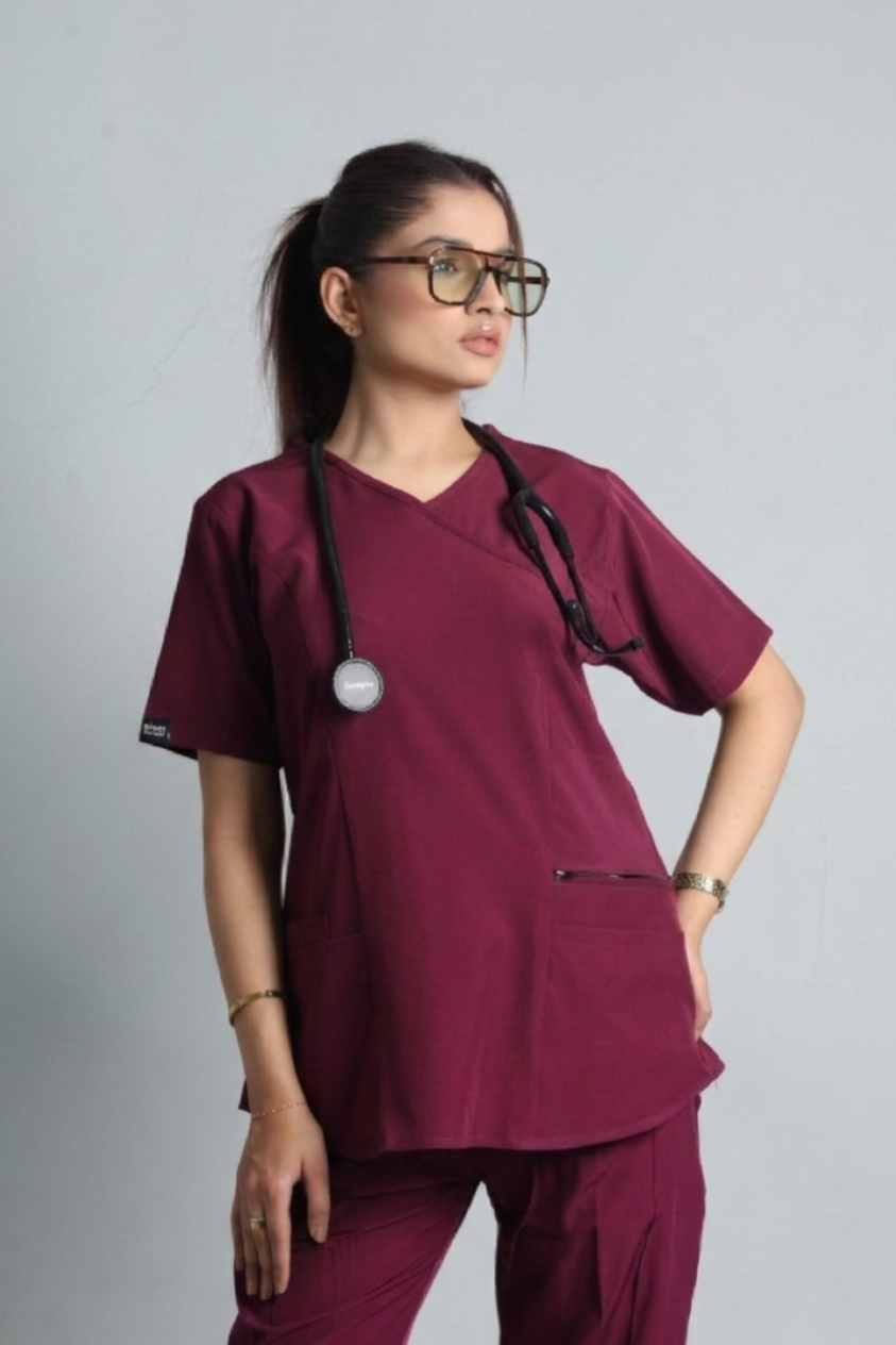 Person wearing maroon medical scrubs with a stethoscope on a gray background